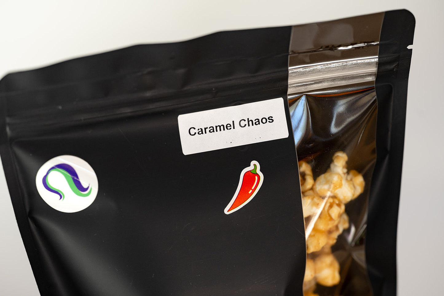 Close-up of TBC Creations Caramel Chaos label and chili pepper sticker on black bag