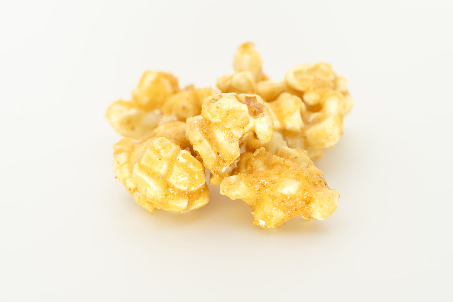 Pile of golden TBC Creations Classic Caramel corn kernels on white background