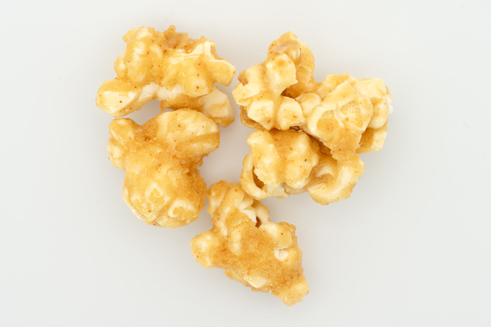 Overhead scatter of TBC Creations Classic Caramel corn kernels on white background