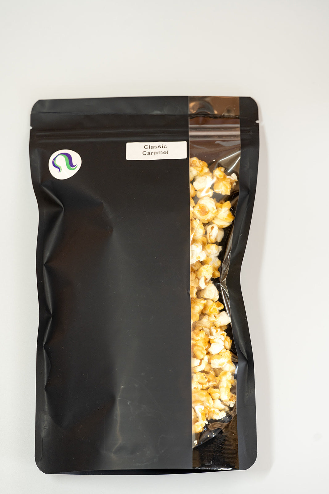 TBC Creations Classic Caramel corn large black bag front view with side window showing product